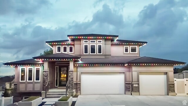 view of front of house with stucco siding, an attached garage, driveway, and stone siding