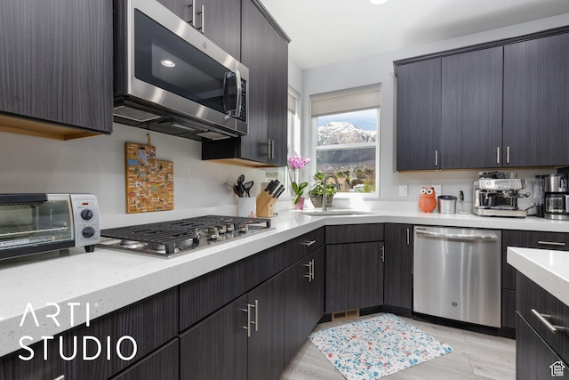 kitchen featuring stainless steel appliances, a toaster, a sink, and light stone counters