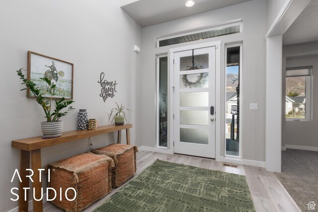 foyer entrance featuring visible vents, baseboards, and wood finished floors