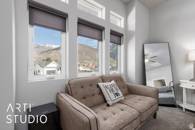 sitting room with a mountain view, a ceiling fan, and a towering ceiling