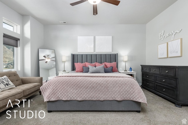 bedroom with visible vents, a ceiling fan, and light carpet