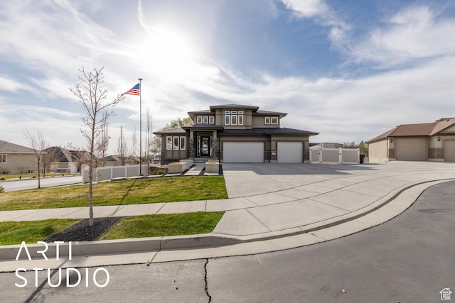prairie-style home featuring a garage, a front yard, stone siding, fence, and concrete driveway