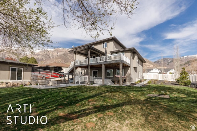 rear view of house with a patio, a yard, a mountain view, and fence