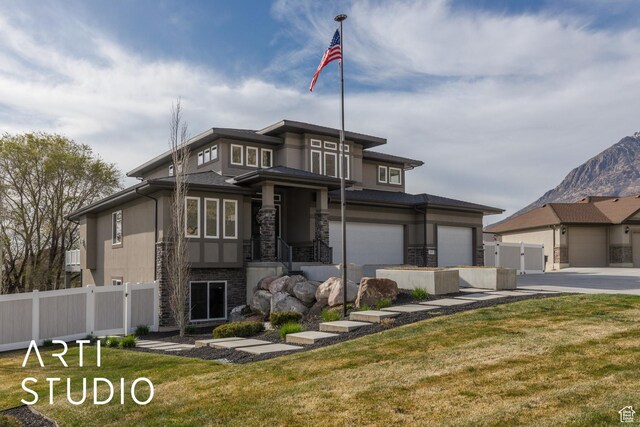 prairie-style home featuring concrete driveway, fence, stone siding, and stucco siding