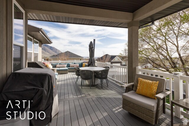wooden terrace featuring a mountain view, grilling area, and an outdoor hangout area