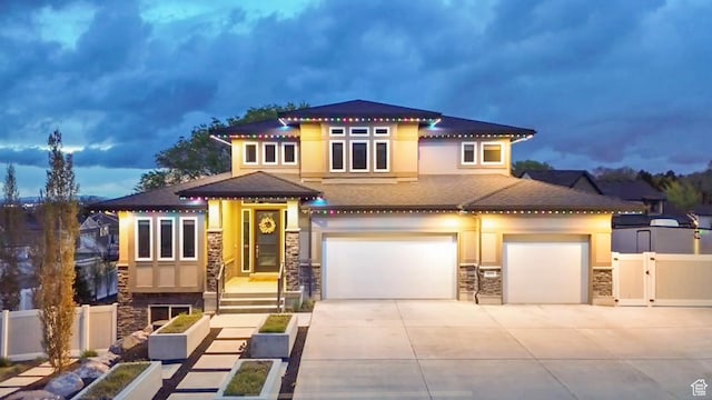 mediterranean / spanish-style house with a garage, stone siding, concrete driveway, and fence