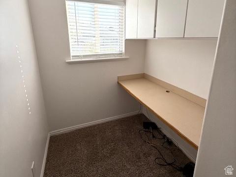 unfurnished office featuring carpet floors, baseboards, and built in desk