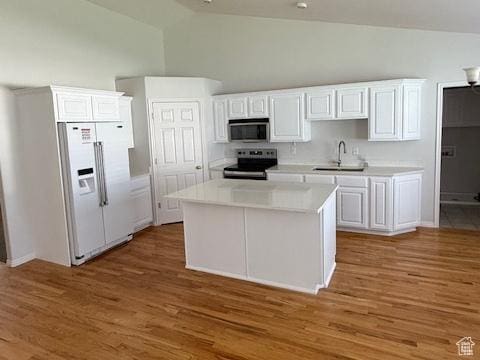 kitchen featuring high vaulted ceiling, light countertops, white cabinetry, a sink, and stainless steel appliances