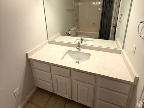 bathroom with tile patterned flooring, vanity, toilet, baseboards, and  shower combination