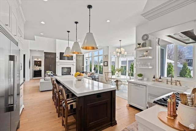 kitchen with high end fridge, light wood finished floors, light countertops, and paneled dishwasher