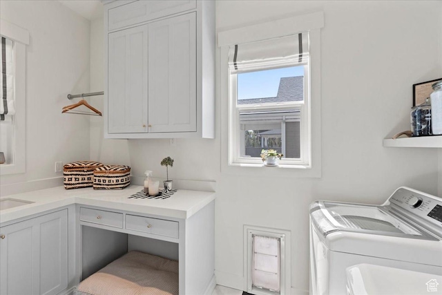 clothes washing area featuring washing machine and clothes dryer and cabinet space