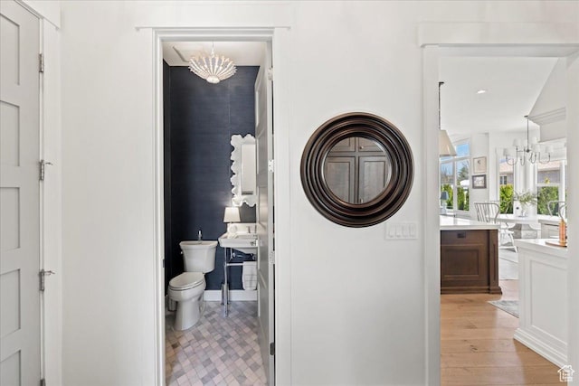 washroom with laundry area, stacked washer and dryer, a notable chandelier, and light wood-style floors