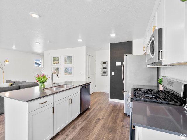kitchen with white cabinetry, wood finished floors, a sink, stainless steel appliances, and baseboards