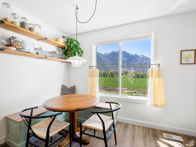 dining area featuring wood finished floors, a mountain view, baseboards, and visible vents