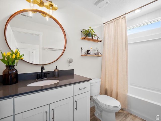 bathroom featuring shower / bath combination with curtain, vanity, visible vents, toilet, and wood finished floors