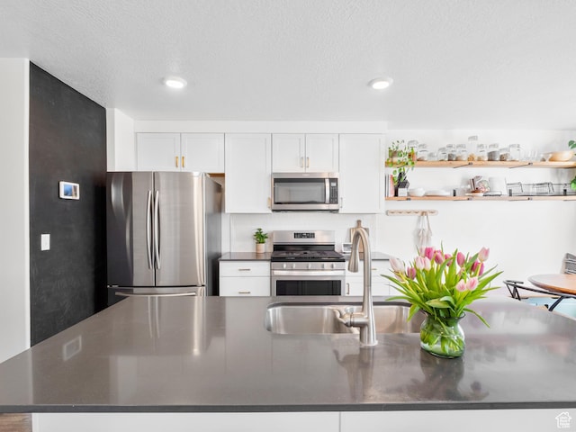 kitchen featuring a sink, dark countertops, white cabinets, and stainless steel appliances