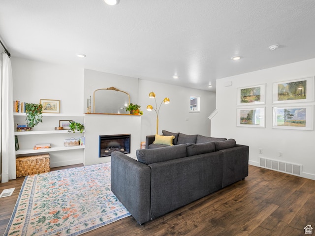 living area featuring visible vents, recessed lighting, a glass covered fireplace, and dark wood finished floors