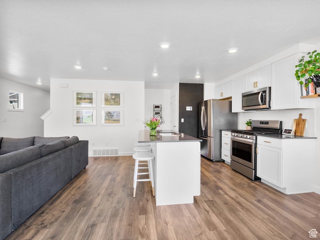 kitchen with stainless steel appliances, open floor plan, visible vents, and dark countertops