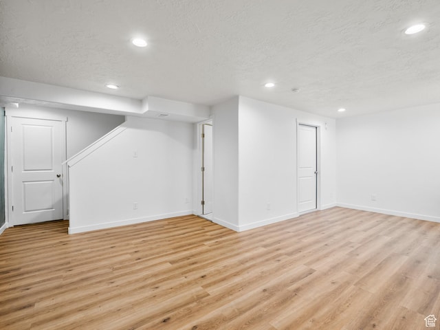 finished below grade area with a textured ceiling, baseboards, and recessed lighting