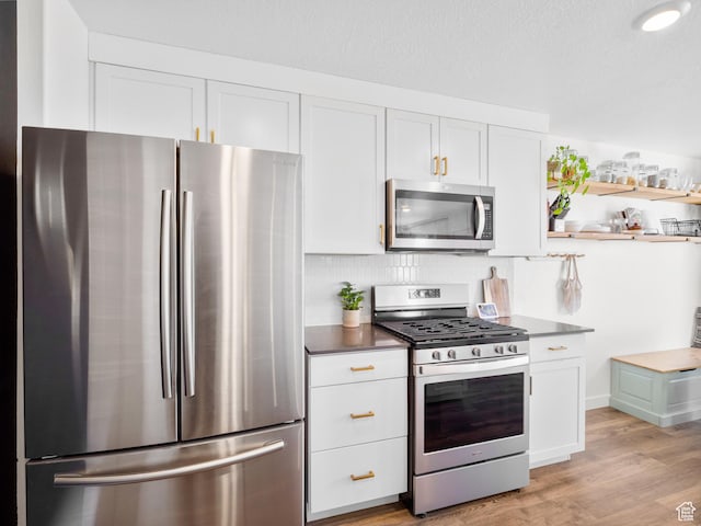 kitchen with light wood-type flooring, white cabinets, and appliances with stainless steel finishes