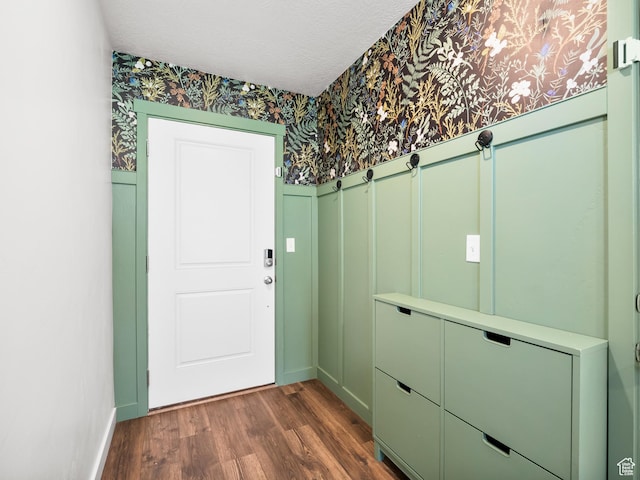 entryway with a decorative wall, wainscoting, wallpapered walls, baseboards, and dark wood-style floors
