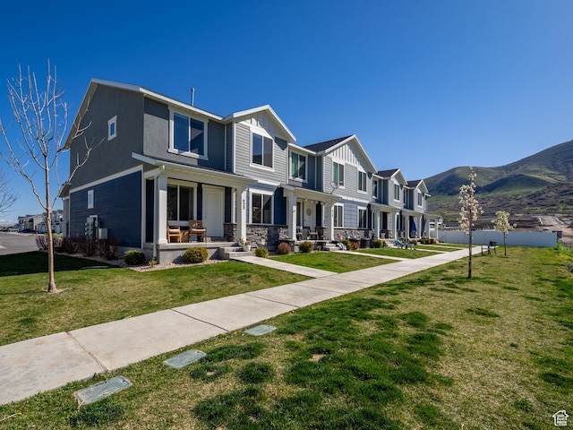 view of front of home featuring board and batten siding, a mountain view, a residential view, and a front lawn
