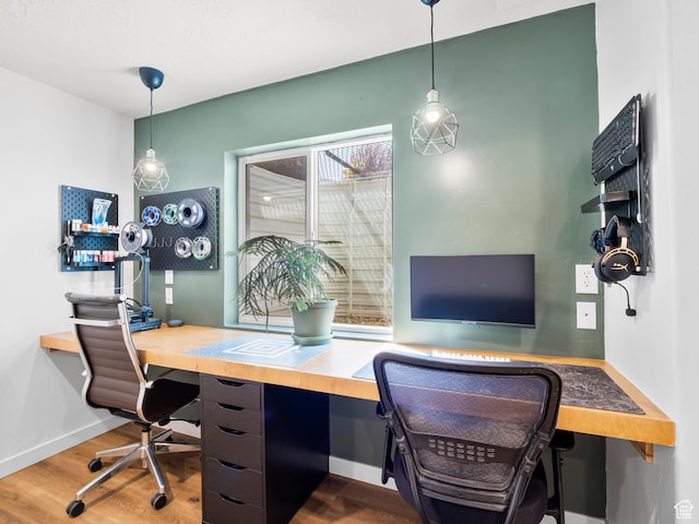 home office with wood finished floors, built in study area, and baseboards