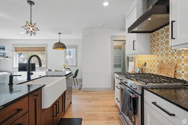 1148 E Kensington Ave, Salt Lake City, UT 84105 - kitchen with wall chimney range hood, backsplash, light wood-style floors, stainless steel appliances, and hanging light fixtures