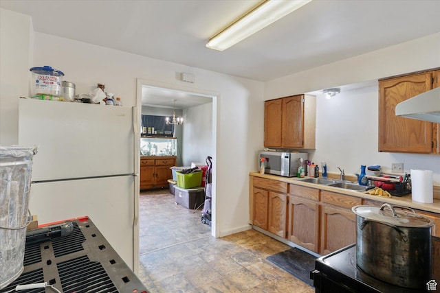 14 E Main St, Goshen, UT 84633 - kitchen featuring stainless steel microwave, light countertops, freestanding refrigerator, brown cabinetry, and a sink