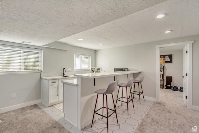 10078 S Shetland Cir S, Jordan, UT 84009 - kitchen featuring a kitchen breakfast bar, a textured ceiling, a peninsula, white cabinets, and a sink