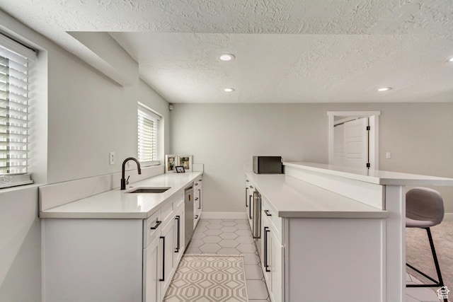 10078 S Shetland Cir S, Jordan, UT 84009 - kitchen with a sink, light countertops, a textured ceiling, recessed lighting, and a breakfast bar area