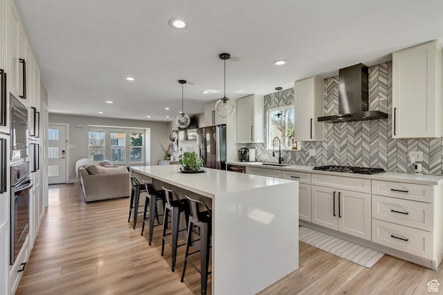 10078 S Shetland Cir S, Jordan, UT 84009 - kitchen featuring a sink, wall chimney range hood, open floor plan, appliances with stainless steel finishes, and a kitchen breakfast bar