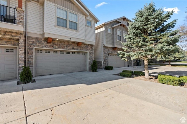 multi unit property with concrete driveway, board and batten siding, a garage, and stone siding