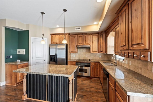 kitchen featuring dark wood-style flooring, under cabinet range hood, visible vents, stainless steel appliances, and a sink