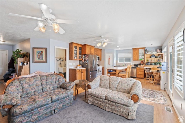 1663 N 2400 W, Clinton, UT 84015 - living room with light wood-style flooring, a textured ceiling, ceiling fan, and visible vents