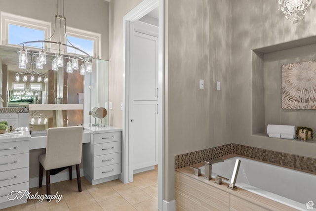 full bath with tile patterned flooring, an inviting chandelier, vanity, and a garden tub