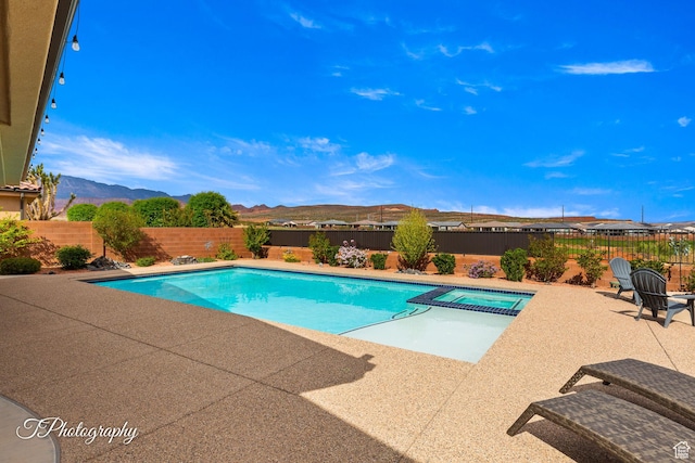 view of swimming pool with a fenced backyard, a mountain view, a patio, and a pool with connected hot tub