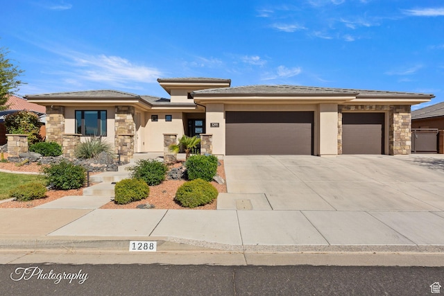 prairie-style home featuring an attached garage, stone siding, stucco siding, and driveway