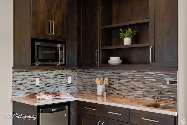 kitchen featuring tasteful backsplash, dark brown cabinetry, stainless steel appliances, and a sink