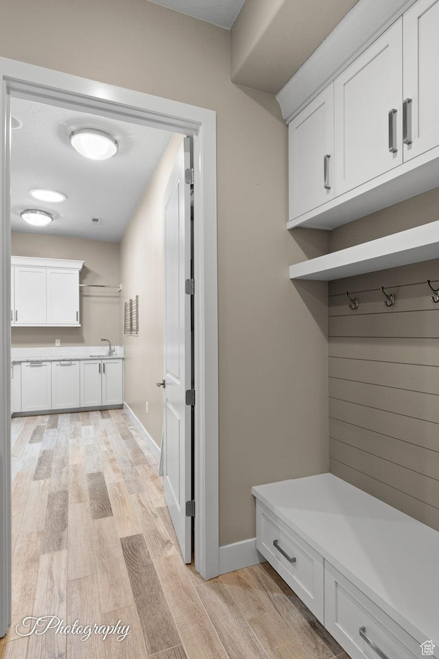 mudroom featuring light wood finished floors and baseboards