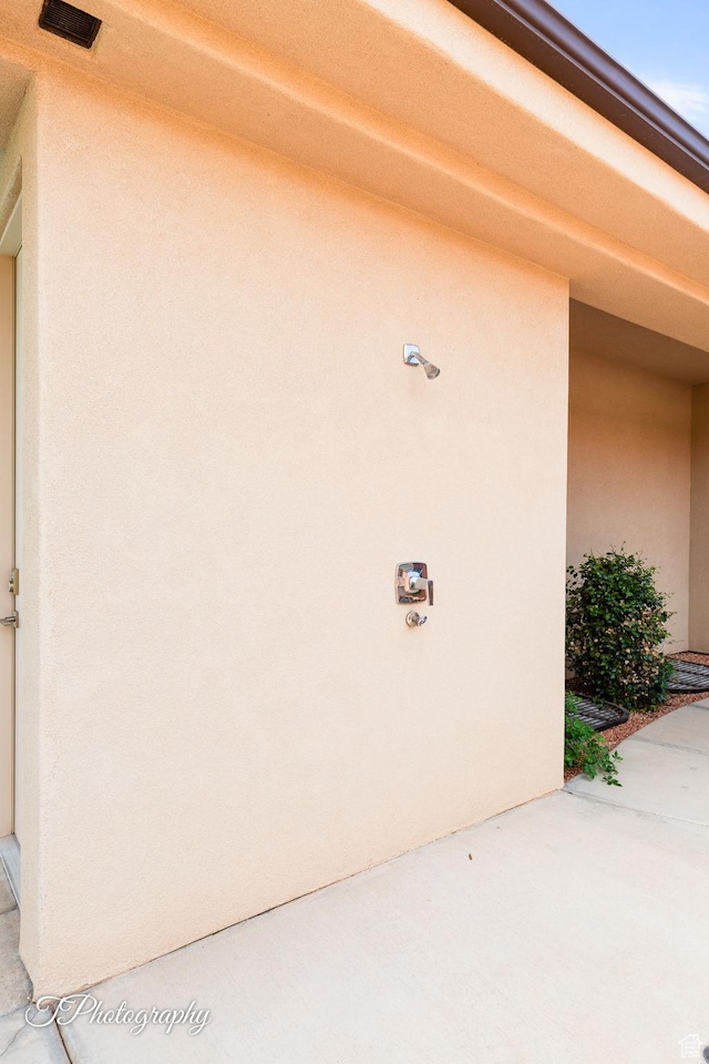 view of exterior entry with stucco siding and visible vents