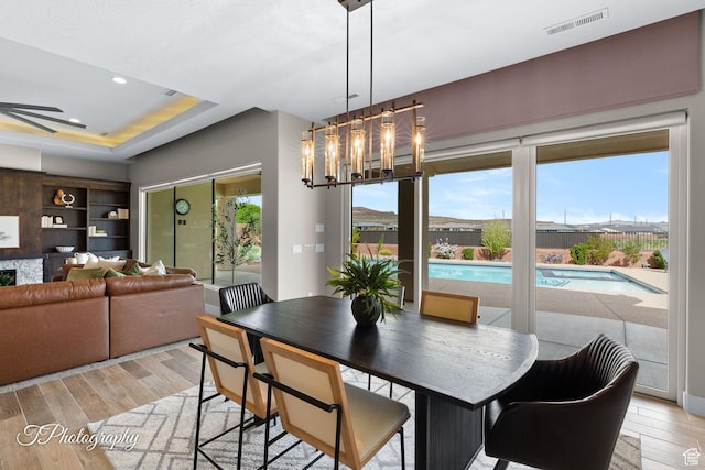 dining area featuring light wood-style flooring, visible vents, recessed lighting, and a tray ceiling