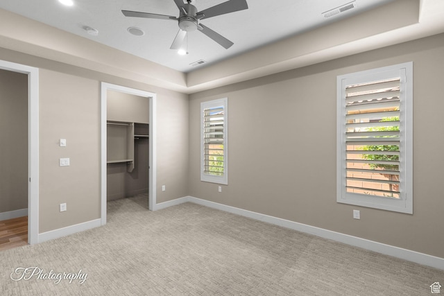 unfurnished bedroom featuring baseboards, visible vents, light colored carpet, a closet, and a walk in closet