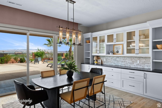 dining room with light wood-style flooring, visible vents, and a notable chandelier