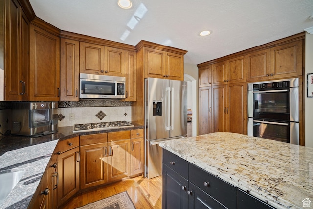 1778 E Indian Wells Ln, Draper, UT 84020 - kitchen with brown cabinetry, light wood-type flooring, decorative backsplash, and stainless steel appliances