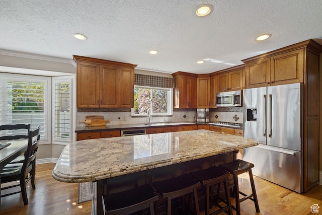 1778 E Indian Wells Ln, Draper, UT 84020 - kitchen with stainless steel appliances, light wood-type flooring, a kitchen bar, and brown cabinets