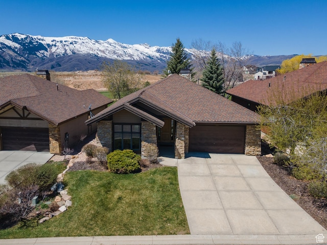 ranch-style house featuring a mountain view, an attached garage, stone siding, and concrete driveway