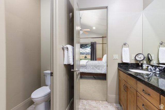 bathroom with vanity, baseboards, vaulted ceiling, ensuite bath, and toilet