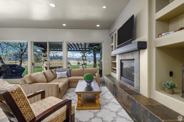 living room featuring built in features, a tile fireplace, plenty of natural light, and recessed lighting
