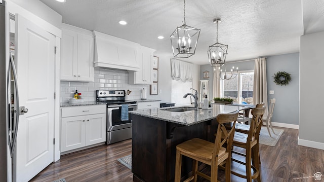 kitchen featuring custom exhaust hood, baseboards, a notable chandelier, a sink, and stainless steel appliances